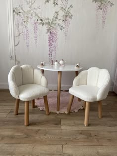 two chairs and a table in front of a wall with flowers painted on the walls