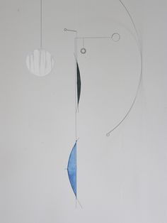 an abstract painting with blue and white shapes hanging from it's sides on a wall