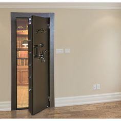 an empty room with a door open to reveal a large bookcase in the corner