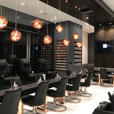 a salon with lots of black chairs and lights hanging from it's ceilings