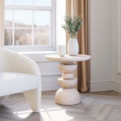 a white chair sitting next to a table with a vase on it