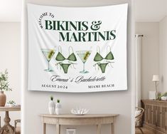 a wedding banner with three martinis on it hanging from the wall in front of a table