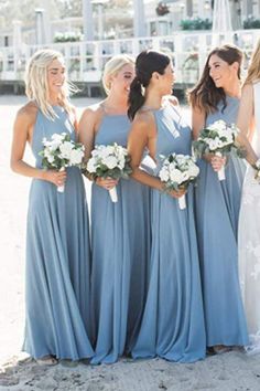 a group of women standing next to each other on top of a sandy beach holding bouquets