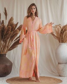 Unveil the harmony of elegance and comfort with our Gabriella Maxi Kaftan. Crafted with love, this piece embodies the ethereal beauty of dawn, gracing your form with its delicate pink hues and golden floral motifs. Every fold and drape of this robe tells a story of tranquility, inviting you to wrap yourself in its gentle embrace. Designed for those serene mornings or tranquil evenings, it becomes a sanctuary for your soul, reminding you of the calm and beauty that surrounds us. Size: Our model i Spring Wrap Robe With Relaxed Fit, Spring Daywear Wrap Robe, Spring V-neck Robe For Loungewear, Wrap Robe For Relaxation In Spring, Spring Wrap Robe For Relaxation, Spring Wrap Robe For Sleep, Spring V-neck Sleep Robe, Spring Wrap Sleep Robe, Spring Wrap Loungewear Robe