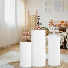 three tall white speakers sitting on top of a wooden floor