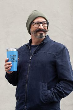 a man with glasses and a hat holding a can