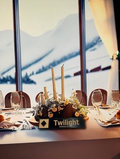 the table is set with candles and place settings in front of large windows overlooking snowy mountains