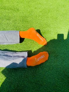 two people wearing orange socks with the word carrots written on them sitting in grass