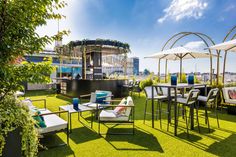 an outdoor seating area with chairs and umbrellas on the grass, next to a bar