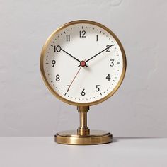 an alarm clock sitting on top of a white table next to a gray wall with red hands