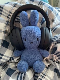 a blue stuffed animal with headphones on it's ears sitting on a bed