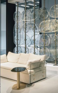 a white couch sitting in front of a glass wall with lots of plates on it