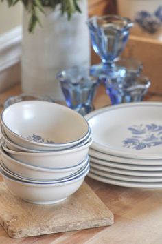 a stack of white plates sitting on top of a wooden table