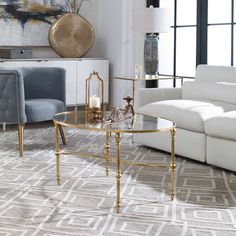 a living room with white couches and gold accents on the coffee table in front of a large window