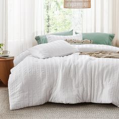 the bed is made with white linens and pillows