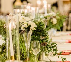 the table is set with candles, flowers and greenery for a festive dinner