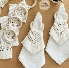 white napkins with tassels on them sitting on a table next to a potted plant