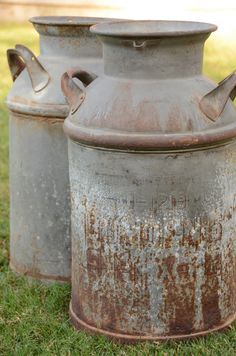 two old metal containers sitting in the grass