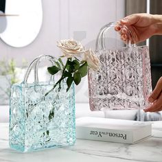 two clear bags with flowers in them sitting on a marble counter top next to each other