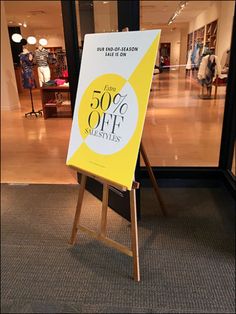 a sign in front of a clothing store advertising 50 % off clothes on the sale