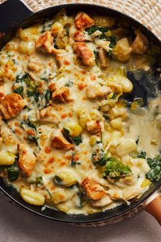 a skillet filled with chicken, spinach and cheese on top of a table