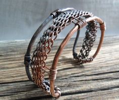 Woven ~  Art imitating lifes interweaving journeys of ups and downs. My depiction is brought to life by using complex metal weaving, colors altered through heating techniques and hammering.   A carefully woven band created from 5 copper wires was placed in the center of a 10 gauge hammered wire frame. I then oxidized one side of the cuff with my gunsmoke patina and polished to a dull shine. I applied a non-yellowing jewelers lacquer to maintain the patina and to discourage against skin discoloration. This cuff bracelet is 6 inches long and 1 inch wide. Handmade Artisan Metal Cuff Bracelet, Handmade Metal Fusion Cuff Bracelet, Handmade Fusion Metal Cuff Bracelet, Handmade Fusion Style Metal Cuff Bracelet, Silver Artisan Cuff Bracelet In Copper, Artisan Silver Cuff Bracelet In Copper, Artisan Silver Copper Cuff Bracelet, Artisan Silver-colored Copper Cuff Bracelet, Jewllery Ideas