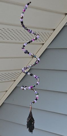 a wind chime hanging from the side of a house with beads and flowers on it