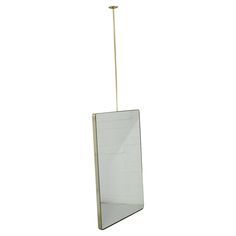 a mirror hanging from a metal pole on a white wall