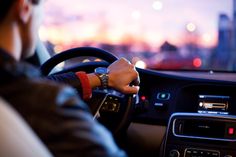 the man is driving his car in the city at night, wearing a watch on his wrist