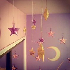 some paper stars hanging from the ceiling in a room with purple walls and white trim