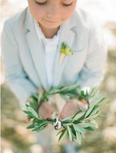 a young boy wearing a suit and holding an olive branch