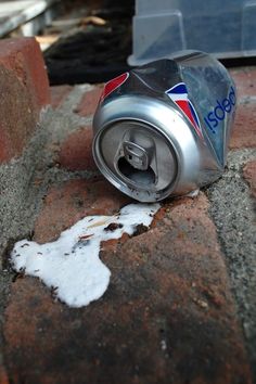 a can of soda sitting on top of a brick wall