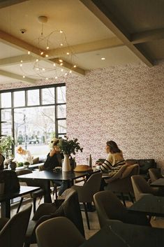 two women sitting at a table in a restaurant with flowers on the window sill