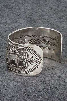 This sterling silver bracelet featuring horses grazing in a Southwestern landscape was made by Navajo silversmith Jeremy Delgarito. The back is signed J Delgarito and stamped sterling.Size: 5 3/8" (will fit up to a 6 3/4" wrist)Gap: 1 3/8"Width: 1 1/4"Free shipping on all orders! We ship with USPS and always include tracking. All orders ship within a day of payment.Returns are accepted up to 30 days after you receive your order. Just send us a message. Our shop offers cash back or store credit. Western Sterling Silver Cuff Bracelet With Concho, Unique Stamped Sterling Silver Collectible Bracelet, Western Sterling Silver Concho Bracelets, Western Sterling Silver Bracelets With Concho, Western Sterling Silver Cuff Bracelet, Western Sterling Silver Bracelets, Southwestern Etched Bracelets For Collectors, Western Style Sterling Silver Cuff Bracelet, Western Style Engraved Sterling Silver Jewelry