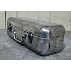 a metal suitcase sitting on top of a cement floor