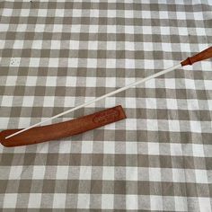 two wooden paddles laying on top of a checkered tablecloth with a white stick sticking out of it