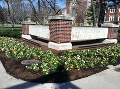 a brick monument with flowers in the foreground