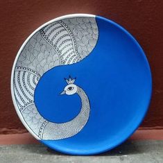 a blue and white plate sitting on top of a cement floor next to a wall