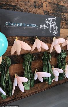 balloons and flowers are hanging on the wall next to a sign that says grab your wings and fly