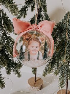 a christmas ornament hanging from a tree with a pink bow on it's head