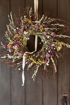 a wreath with flowers hanging on a door