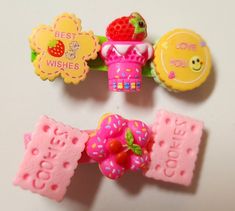 three different types of hair clips on a white surface, one has strawberrys and the other has candy