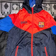 Never Worn Barcelona Soccer Swishy Jacket Red Sports Outerwear, Red Sportswear Hooded Jacket For Sports, Red Outerwear For Sports Events, Casual Red Sport Coat, Casual Blue Outerwear For Sports Events, Red Hooded Outerwear For Sports Events, Red Sportswear Outerwear For Sports Events, Red Sportswear Outerwear For Outdoor Activities, Red Casual Windbreaker For Sports Events