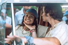 a man and woman sitting in the driver's seat of a car talking to each other