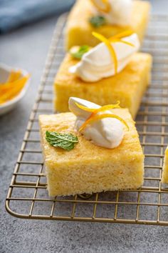 three pieces of cake sitting on top of a cooling rack next to orange slices and whipped cream