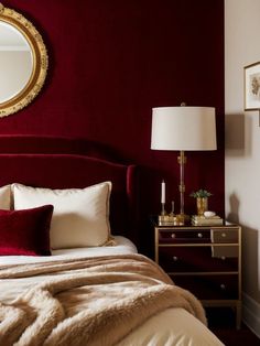 a bedroom with red walls, gold accents and a white bed topped with a maroon comforter