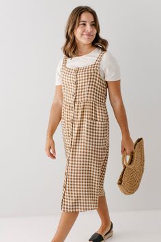 Whether it's a day at the park or a picnic on the beach, the 'Cora' Cotton Pinafore Dress will be your new go-to in your wardrobe for the warmer weather! Featuring a simple gingham design and a comfortable silhouette, you can pair this with a pair of sandals and a handbag for a chic vacation look. Exclusively designed by us with you in mind! 100% Cotton Hand Wash in Cold Water Do Not Bleach Iron on Low Heat Hang Up or Lay Flat to Dry Do Not Dry Clean Fully Lined Model Height 5'6" | Wearing Size Small Please carefully measure a similar item before placing your order to allow for the best fit and also to reduce the risk of returns. Have questions about fit? Call us! We try everything on, so we know how our clothes fit and we’re happy to assist you. Customer Service: 717.598.8309 9 AM - 3 PM Preppy Knee-length Summer Dresses, Casual Plaid Dress For Beach, Casual Brown Dress For Picnic, Plaid Sundress For Vacation, Casual Gingham Plaid Dress For Vacation, Casual Sundress For Summer Picnic, Casual Knee-length Sundress For Picnic, Casual Midi-length Plaid Dress For Day Out, Casual Plaid Midi-length Dress For Day Out