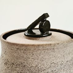 a black object sitting on top of a white table next to a gray cup and saucer