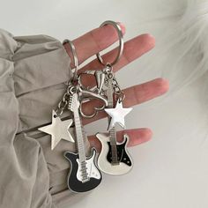 a person is holding two guitar key chains in their hand, one has an electric guitar and the other has a star on it