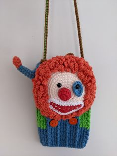 a crocheted bag with a clown face hanging from it's front end